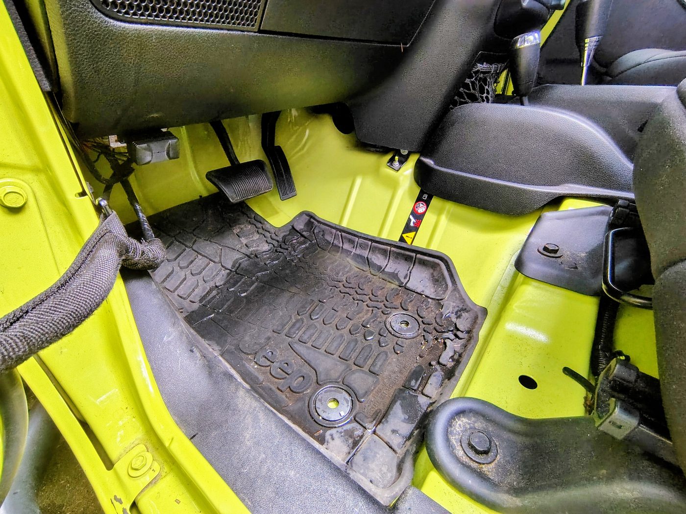 A Jeep floor pan and mat in the footwell where water collects after a leak